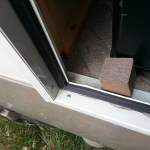 A cube of Trex from a deck left-over and a recycled hinge.  Flip it up and the fridge stays closed.