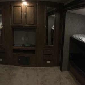 Panaramic picture of the bunk room at back.  1 larger bunk on left, smaller bunk on right, with a fold down (futon style) couch under it (in a shadow 