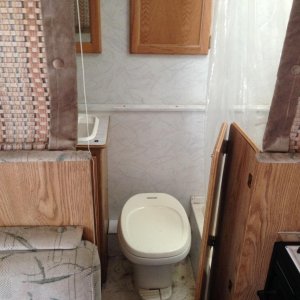 bathroom, toilet, shower, closet, and sink. storage cabinets