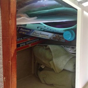 Bottom storage space in closet.  Tote is for going to shower house, but for now has clothes hamper folded in it.  Basket on left has extra bath towels