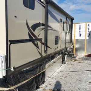 Awning and door side of Fun Finder 28qd with 2 inch Styrofoam reflective insulation covered in black plastic held on by bungee cords and ratchet strap