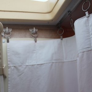 I attached adhesive backed hooks to each end of the shower and used curtain ring clips to attach the curtain to the existing ceiling track and the wal