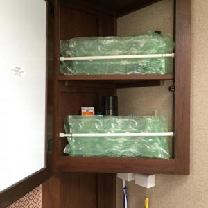 For traveling purpose only, we use an expandable curtain rod along with packaging bubbles to keep items in the medicine cabinet upright.