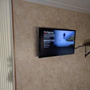 24" smart TV mounted in bedroom at foot of the bed.