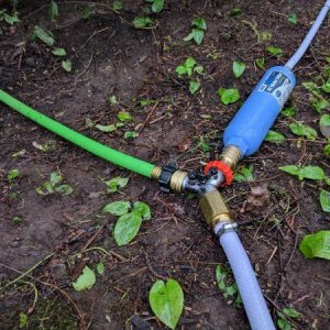 Water connection.  White line is from the well.  Goes to a shutoff valve and then a spliter.  First line goes into a back-flow preventer and then a ga