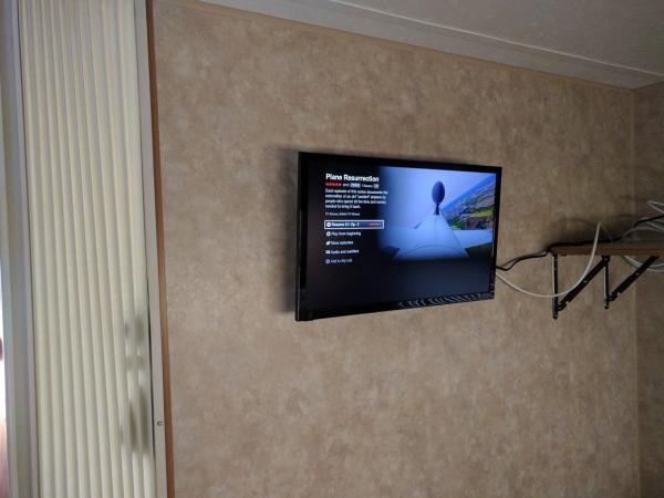 24" smart TV mounted in bedroom at foot of the bed.