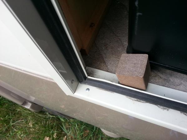 A cube of Trex from a deck left-over and a recycled hinge.  Flip it up and the fridge stays closed.