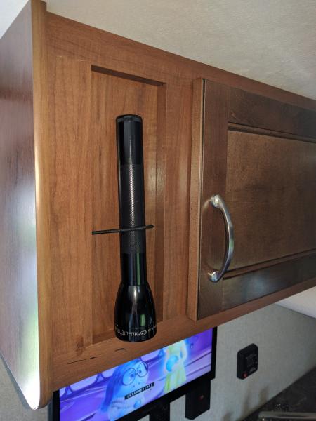 Added bungee cord through wood panel to hold flashlight.  Also visible, the TV.