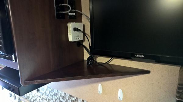 Angle shelf under TV for holding charging phones