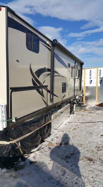 Awning and door side of Fun Finder 28qd with 2 inch Styrofoam reflective insulation covered in black plastic held on by bungee cords and ratchet strap