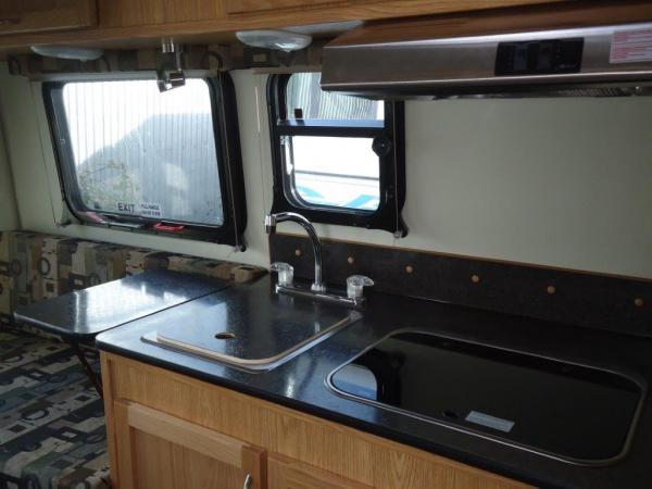 Black counter top, stainless hood, and SMEV stove.