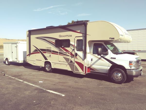 Brownie with old trailer in parking lot.