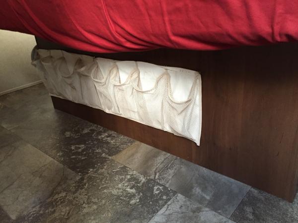 Cut and mounted a hanging shoe bag under the bed using industrial Velcro.