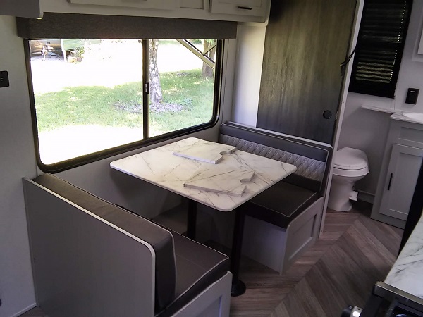 dinette with big window and sink cover/counter laying on table.  It turns into a small bed.