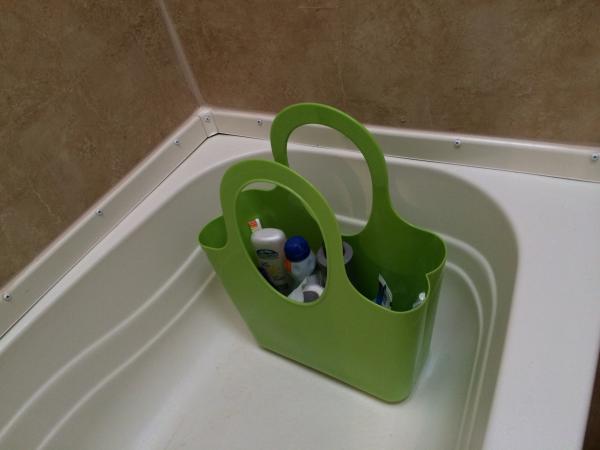 Dollar store plastic basket sits in the tub with shower goodies, extra sunscreen, etc inside.