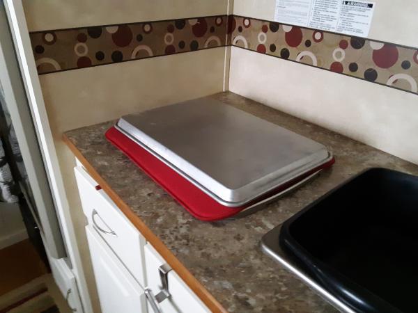 I cover the stove with a dish drying pad and a metal tray that gives me work kitchen work surface.  The pad keeps it in place while traveling.