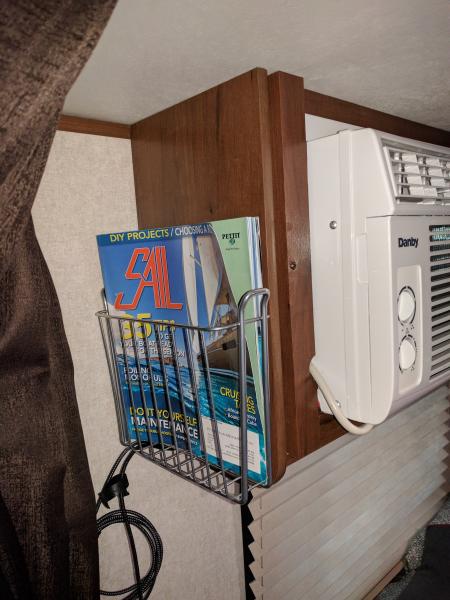 Magazine rack on the side of the AC unit over queen bed.  Used to hold reading material and phone charging cords.