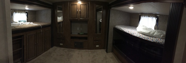 Panaramic picture of the bunk room at back.  1 larger bunk on left, smaller bunk on right, with a fold down (futon style) couch under it (in a shadow 