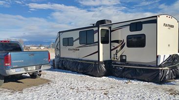 Pullout side of Fun Finder 28qd with 2 inch Styrofoam reflective insulation covered in black plastic held on by bungee cords and ratchet straps. The b