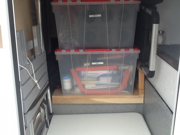 Rear passenger side bay door. Two tote boxes, folding table, ladder, dinette bed brace, outdoor table.