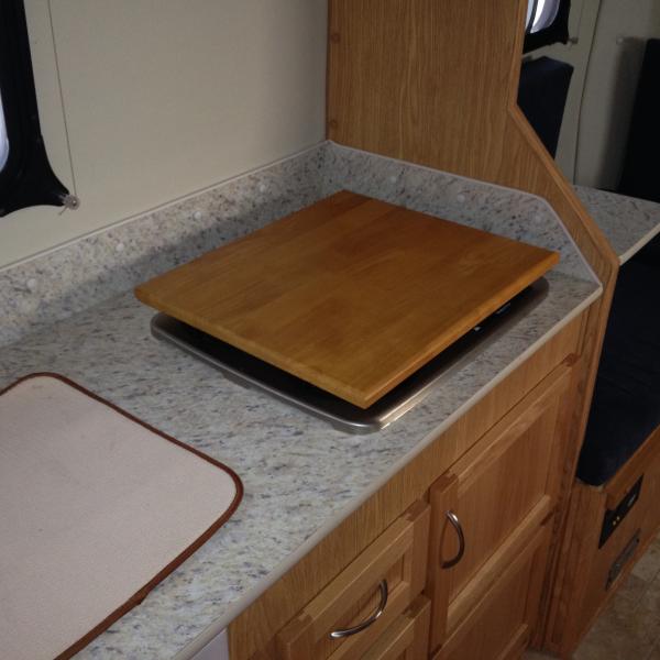 SallyP had this installed. it works great as a cutting board as well.

http://www.amazon.com/Camco-43521-Accents-Universal-Stovetop/dp/B000EDUTX6