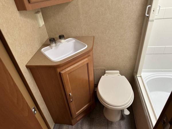 Small but functional bathroom. Porcelain Dometic foot-operated toilet. Corner sink and medicine cabinet. Shower has a skylight and a small, round vent