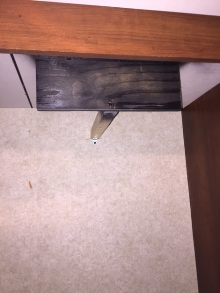 This wooden bracket is at the top of the fridge to keep it from bouncing or tilting forward.  This bracket is why you need to raise the wheels, which 