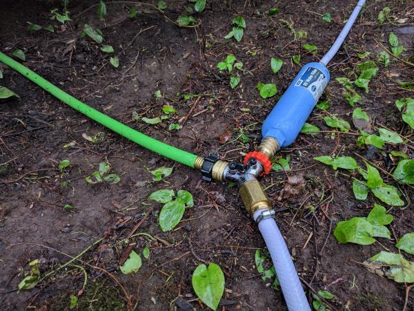 Water connection.  White line is from the well.  Goes to a shutoff valve and then a spliter.  First line goes into a back-flow preventer and then a ga