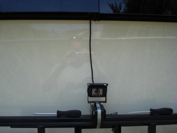 Wireless RV camera attached to back of camper (wire seen goes to 12v source in camper and to the wireless transmitter inside window.